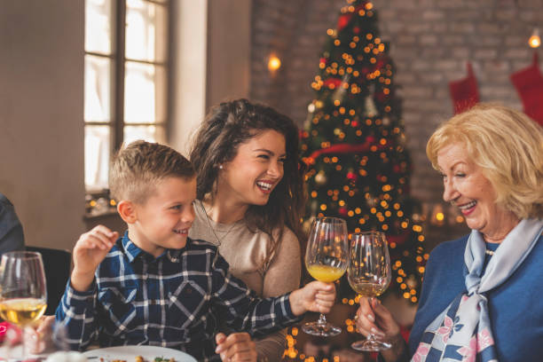 nieto y abuela haciendo un brindis durante la cena de navidad - los niños y los padres brindis bebidas mientras almuerza fotografías e imágenes de stock