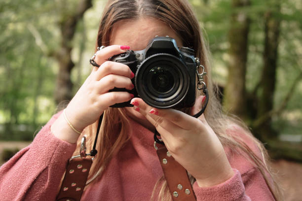 istock Young woman using a DSLR camera in a forest 1271295590