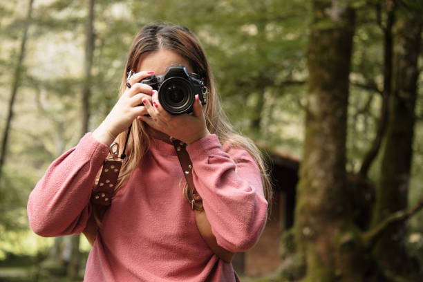 istock Young woman using a DSLR camera in a forest 1271295668