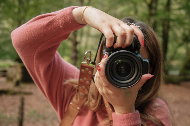 istock Young woman using a DSLR camera in a forest 1271296280