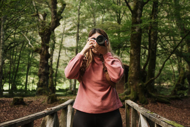 istock Young woman using a DSLR camera in a forest 1271296307