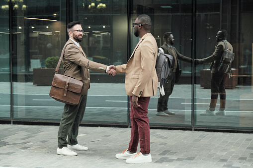 Two colleagues greeting each other during their meeting in the city outdoors