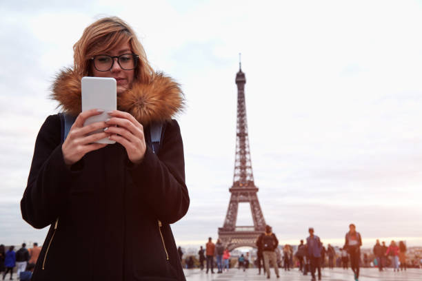istock Girl using cellphone with Paris city background and Eiffel tower. 1271298538