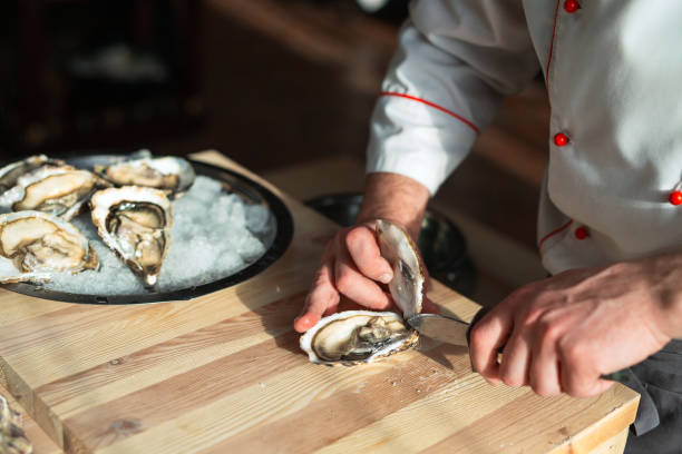 Opening the hollow and flat oysters. Chef opens oysters in the restaurant. stock photo