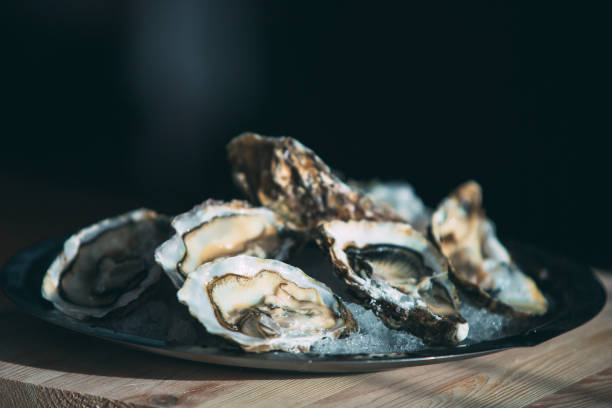 istock Oysters on the black plate on wooden background. 1271300666