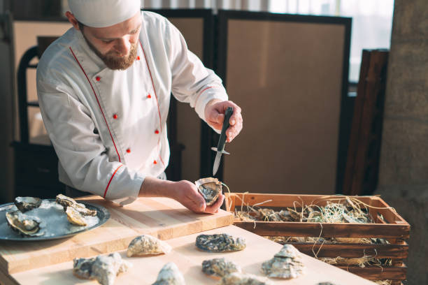 中空と平らなカキを開きます。シェフはレストランで牡蠣を開きます。 - prepared oysters prepared shellfish shucked seafood ストックフォトと画像