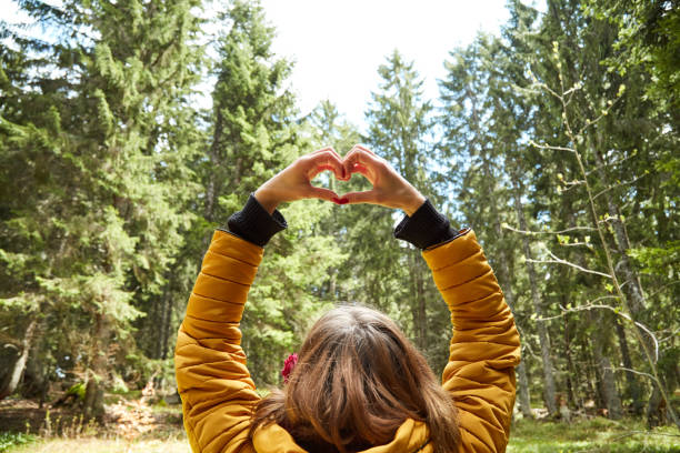 mujer con símbolo en forma de corazón que se sostiene en el aire en el entorno natural. - heart shape loneliness women praying fotografías e imágenes de stock