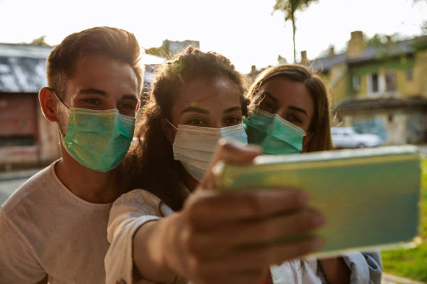 istock Three friends in protective face masks taking selfies 1271302332