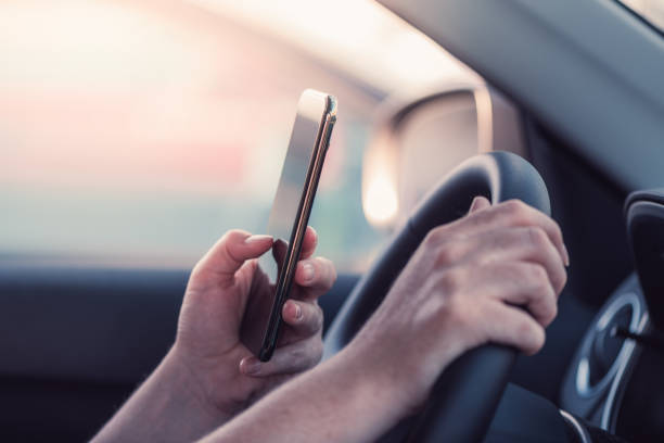 istock Woman texting on mobile phone in the car while holding steering wheel 1271304356