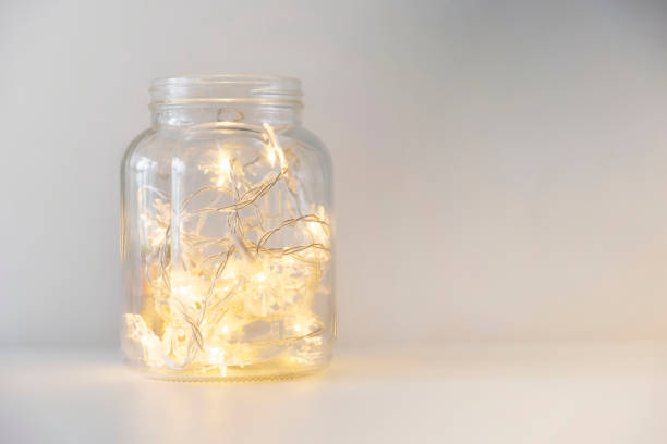 Yellow christmas lights in a glass jar on a white background