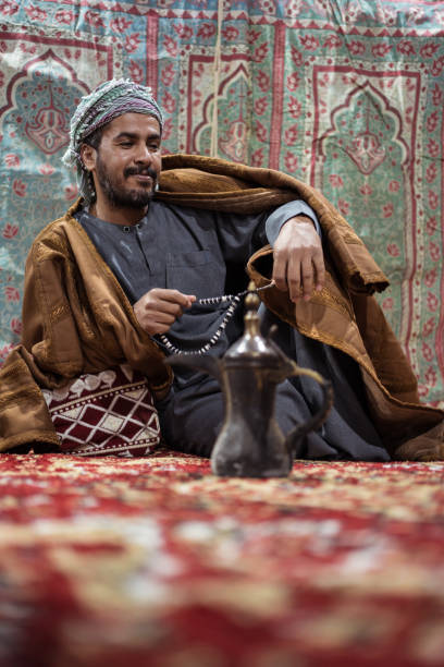 istock Bedouin man wearing traditional clothes praying with a tasbih while drinking tea on a carpet in the Saudi desert 1271307909