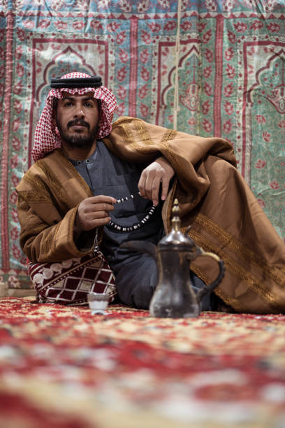 istock Bedouin man wearing traditional clothes praying with a tasbih while drinking tea on a carpet in the Saudi desert 1271307995