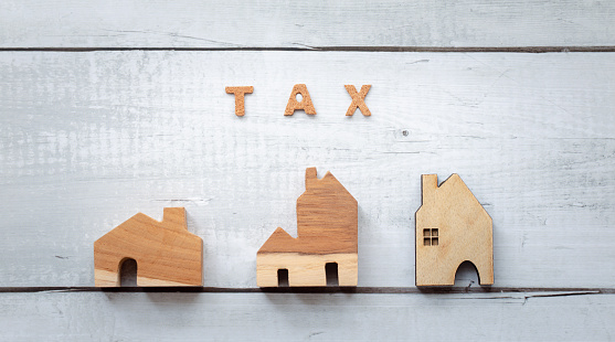 top view tax word with wooden home models on white wood background, tax concept