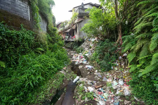 Bali / Indonesia - August 15, 2018: river full of garbage and plastics as it passes through village in Bali