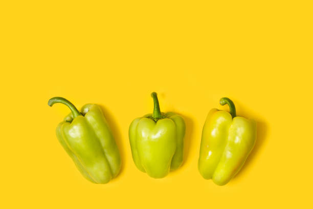 Light green peppers isolated on a yellow background in a top view