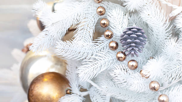 istock White artificial Christmas tree decorated with a silver pine cone, shiny balls and a golden shimmering garland. festive Christmas background decorations. Underlay for flyer and advertising poster 1271314327