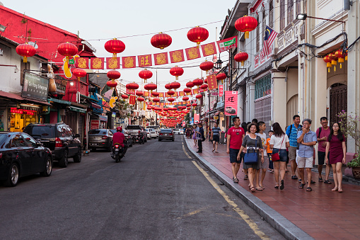 Malacca / Malaysia - February 16, 2019: group of tourists strolling the streets of Malacca with red lanters hanging over the street during Chinese New Year celebrations