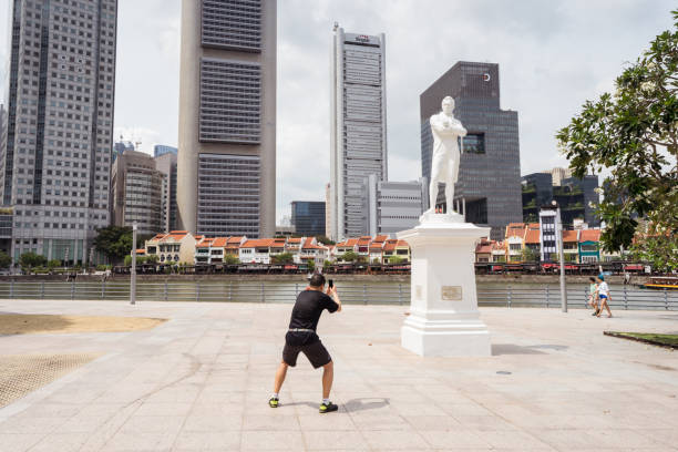 turista asiatico che scatta foto di scultura in una posizione strana nella città di singapore - editorial asia singapore tourist foto e immagini stock