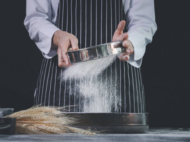 istock Bakery man sifting flour into a bowl, preparing bread dough, kneading the dough. Hands with flour splash, food homemade bakery concept 1271319411