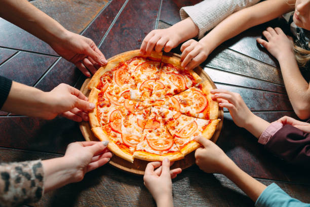 istock Hands taking pizza slices from wooden table, close up view. 1271319458
