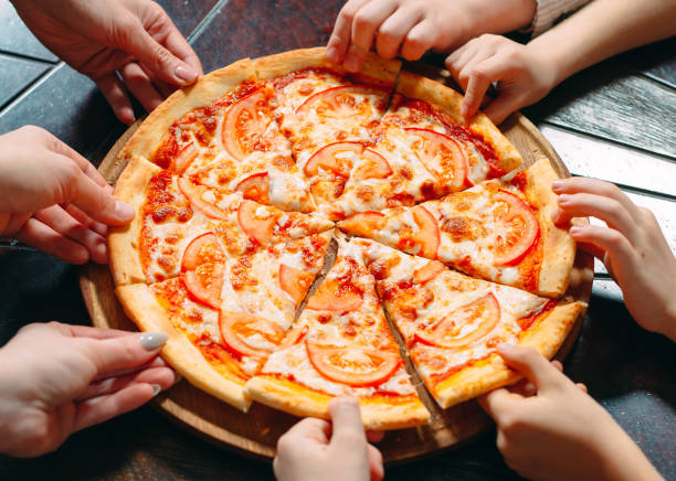 istock Hands taking pizza slices from wooden table, close up view. 1271319467