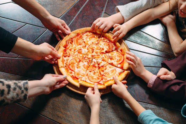 istock Hands taking pizza slices from wooden table, close up view. 1271319478