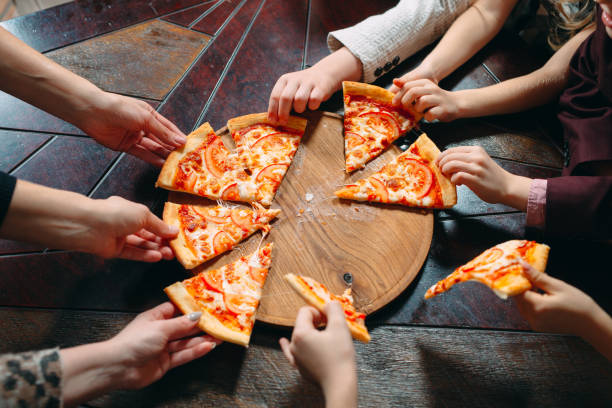 istock Hands taking pizza slices from wooden table, close up view. 1271319517