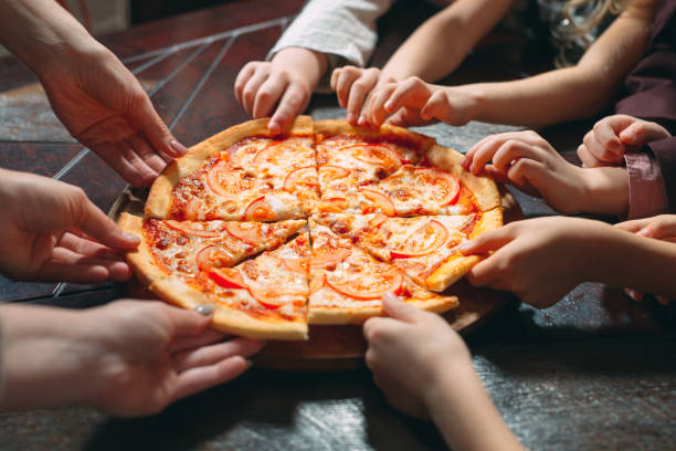 istock Hands taking pizza slices from wooden table, close up view. 1271319524