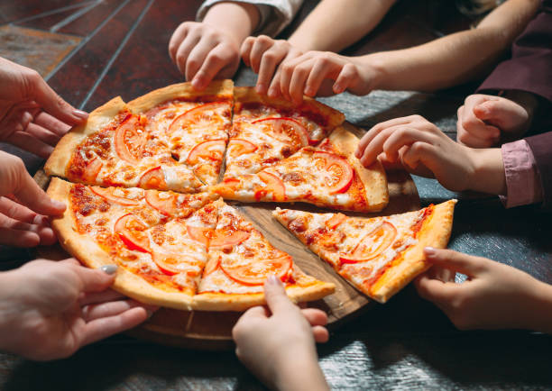 istock Hands taking pizza slices from wooden table, close up view. 1271319533