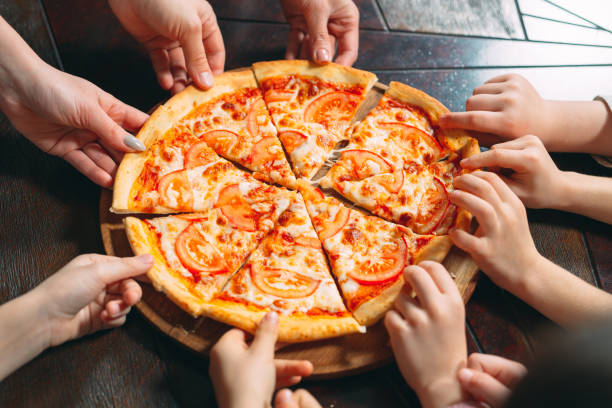 istock Hands taking pizza slices from wooden table, close up view. 1271319549