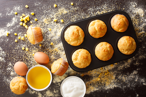 Healthy corn muffins in a baking dish and ingredients close-up on the table. horizontal top view from above