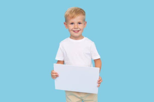 istock A cute laughing child boy is holding a white signboard with an empty space for text. Advertising of childrens products and the announcement of discounts and sales 1271321060