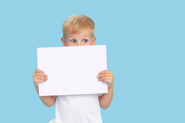 istock A cute laughing child boy is holding a white signboard with an empty space for text. Advertising of childrens products and the announcement of discounts and sales 1271321063