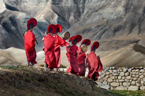 junge mönche laufen gegen die hinterrunde der berge, um an der abschlusszeremonie des tigi-festivals in der hauptstadt lo mantang des königreichs mustang, nepal, teilzunehmen. - tibetan buddhism stock-fotos und bilder