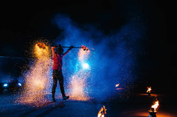 istock Fire show, dancing with flame, male master juggling with fireworks, performance outdoors, draws a fiery figure in the dark, bright sparks in the night. A man in a suit LED dances with fire. 1271322879