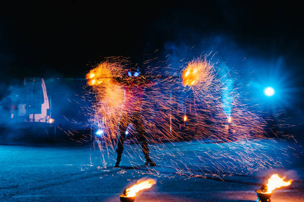 istock Fire show, dancing with flame, male master juggling with fireworks, performance outdoors, draws a fiery figure in the dark, bright sparks in the night. A man in a suit LED dances with fire. 1271322881