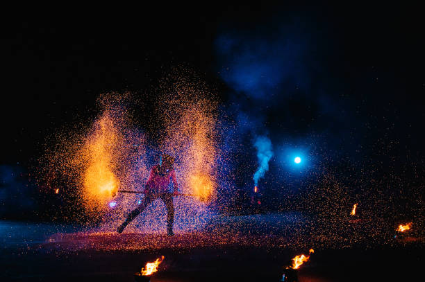istock Fire show, dancing with flame, male master juggling with fireworks, performance outdoors, draws a fiery figure in the dark, bright sparks in the night. A man in a suit LED dances with fire. 1271322886