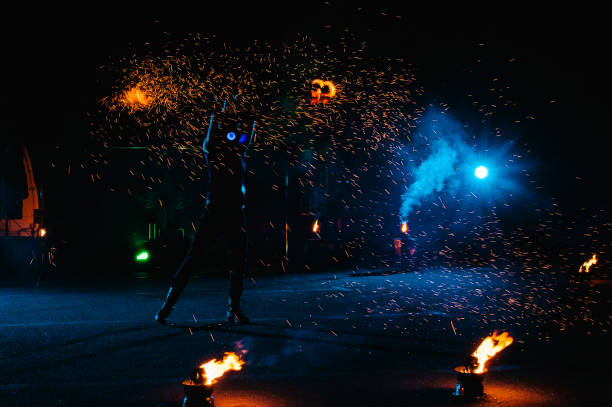 istock Fire show, dancing with flame, male master juggling with fireworks, performance outdoors, draws a fiery figure in the dark, bright sparks in the night. A man in a suit LED dances with fire. 1271322887