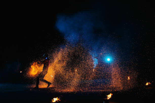 istock Fire show, dancing with flame, male master juggling with fireworks, performance outdoors, draws a fiery figure in the dark, bright sparks in the night. A man in a suit LED dances with fire. 1271322889