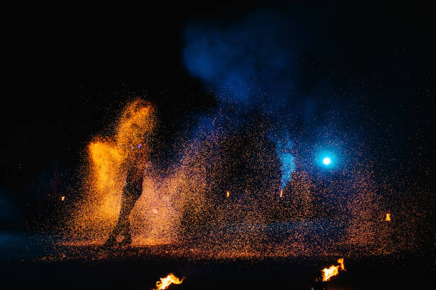 istock Fire show, dancing with flame, male master juggling with fireworks, performance outdoors, draws a fiery figure in the dark, bright sparks in the night. A man in a suit LED dances with fire. 1271322892
