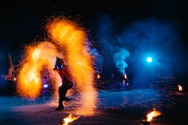 istock Fire show, dancing with flame, male master juggling with fireworks, performance outdoors, draws a fiery figure in the dark, bright sparks in the night. A man in a suit LED dances with fire. 1271322894
