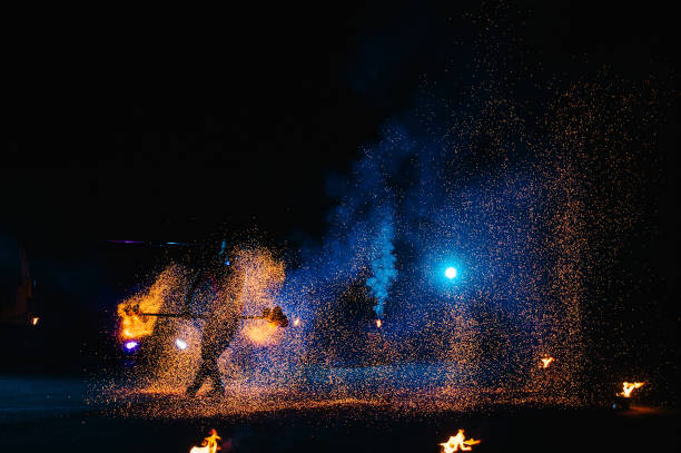 istock Fire show, dancing with flame, male master juggling with fireworks, performance outdoors, draws a fiery figure in the dark, bright sparks in the night. A man in a suit LED dances with fire. 1271322895