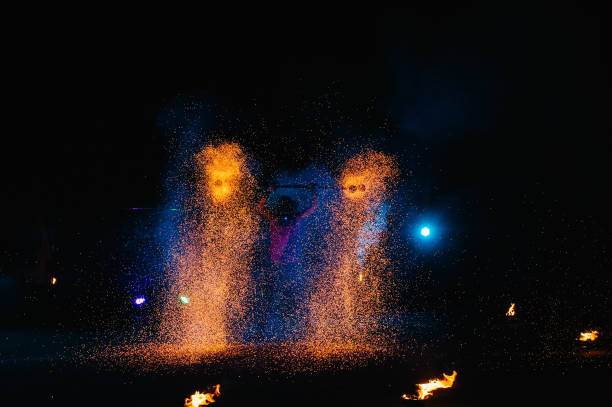 istock Fire show, dancing with flame, male master juggling with fireworks, performance outdoors, draws a fiery figure in the dark, bright sparks in the night. A man in a suit LED dances with fire. 1271322896