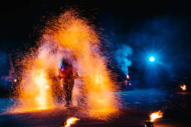 istock Fire show, dancing with flame, male master juggling with fireworks, performance outdoors, draws a fiery figure in the dark, bright sparks in the night. A man in a suit LED dances with fire. 1271322897