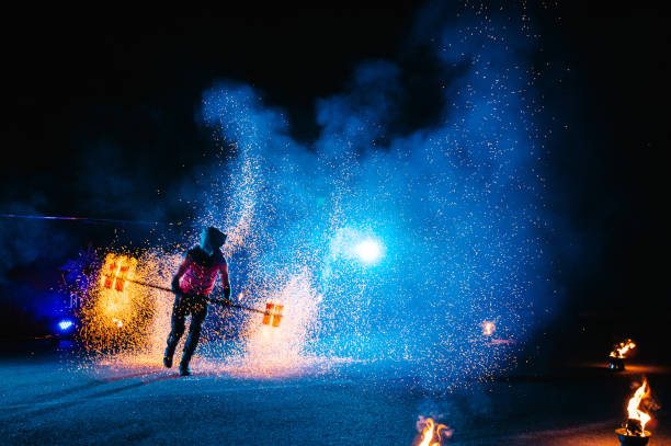 istock Fire show, dancing with flame, male master juggling with fireworks, performance outdoors, draws a fiery figure in the dark, bright sparks in the night. A man in a suit LED dances with fire. 1271322899
