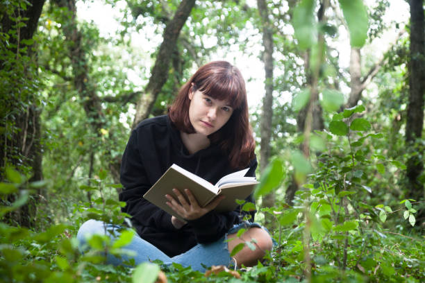 istock Girl sitting in forest reading 1271324652