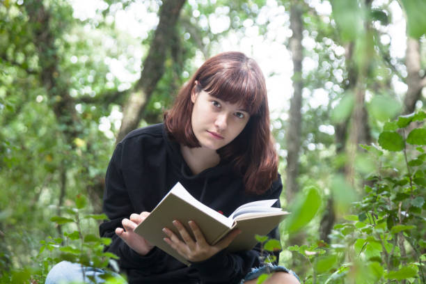 istock Girl sitting in forest reading 1271324658