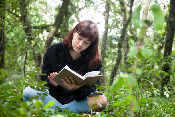 istock Girl sitting in forest reading 1271324662