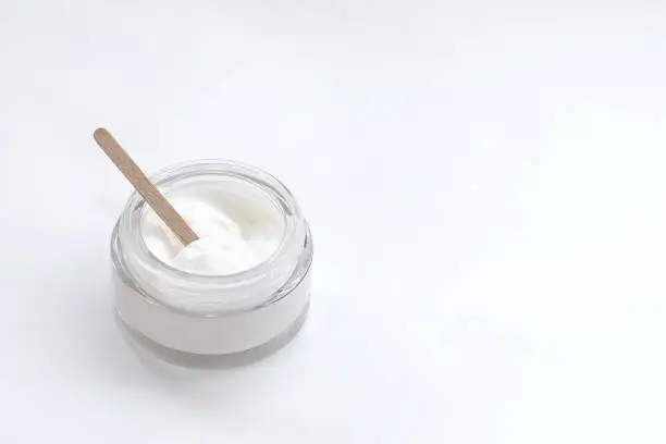 Photo of Glass jar with cream and a wooden stick made at home to nourish the skin.