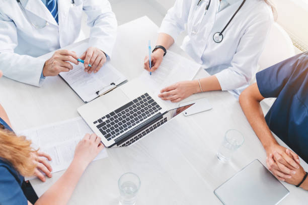 vue supérieure de l’équipe de médecin réussie discutant le diagnostic pendant la conférence dans la salle de réunion - pratique médicale photos et images de collection